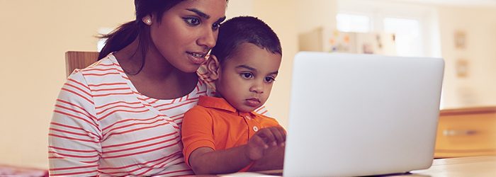 Adult with child using a laptop together in a home setting